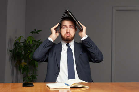 Unhappy businessman with laptop in officeの写真素材