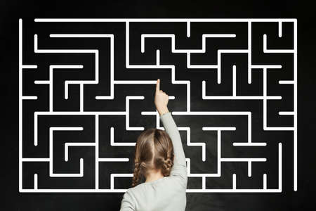 Child girl with labyrinth on blackboard background