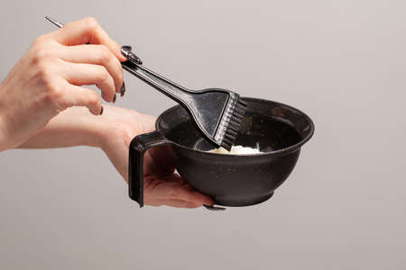 Hair dye preparation. Hands preparing a hair dye in a containerの写真素材