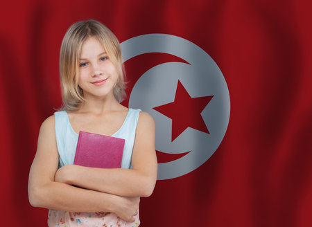 Portrait of cute young girl with book on Tunisian flag backgroundの写真素材