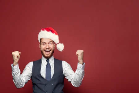 Happy excited businessman in Christmas hat laughing on red banner background portrait.の写真素材