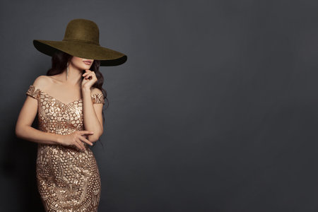 Young brunette fashion model woman with brown wide broad brim hat on black backgroundの写真素材