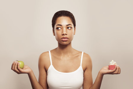Attractive woman holding cake and green apple fruit. Diet and healthy eating conceptの写真素材