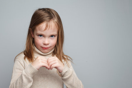 Cheerful smiling little girl looking at camera on gray backgroundの写真素材