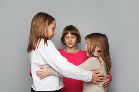 Happy kids embracing on gray backgroundの写真素材