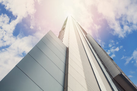 Futuristic skyscarper of steel and glass on the background of sky and sunlightの写真素材