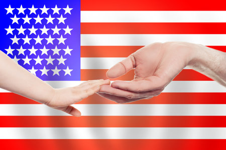 American baby and parent hands on the background of flag of USA Help, aid, support, charity conceptの写真素材