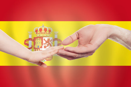 Spanish baby and parent hands on the background of flag of Spanish Help, aid, support, charity conceptの写真素材