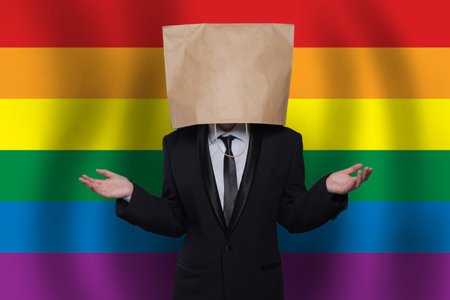 Businessman with paper bag on head on the background of LGBT flag. Equality, diversity, freedom conceptの写真素材