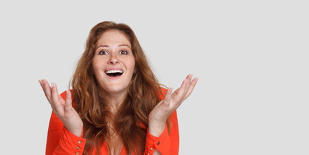 Surprised attractive redhead woman with opened mouth looking at camera on white studio backgroundの写真素材