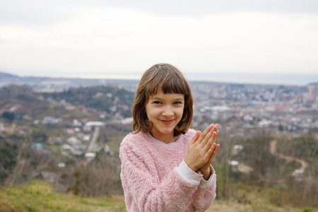 Happy child girl against spring nature background outdoorsの写真素材