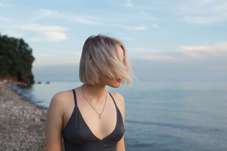 Young blonde woman on the background of sea and cloudy sky portrait, hair in motionの写真素材