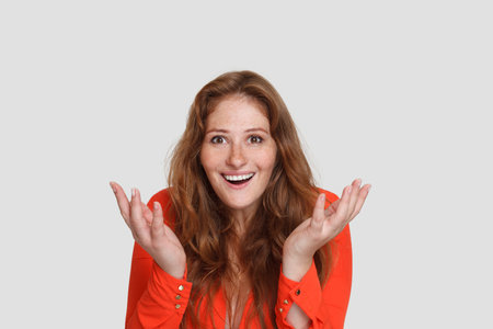 Beautiful redhead woman shacking her hands on white studio background