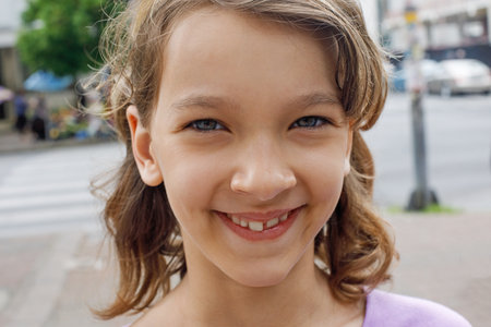 Closeup portrait of funny happy child girl with cute smile outdoorの写真素材