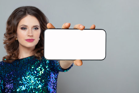 Female hand holding smartphone with empty white screen display on gray backgroundの写真素材