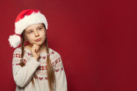Santa child girl thinking on red backgroundの写真素材