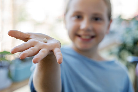 Milk tooth fell out on the hand of adorable child girl. Dental hygiene conceptの写真素材