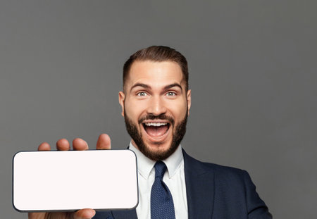 Happy handsome businessman holding smartphone with empty white screen displayの写真素材