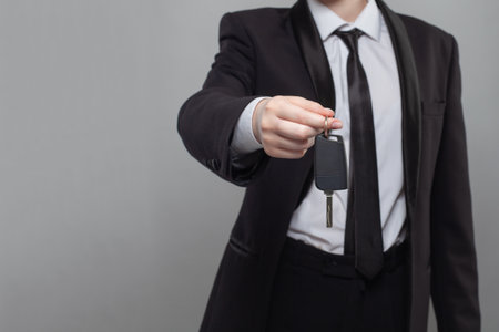 Car key. Businessman holding the car key on gray background