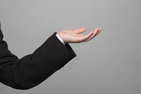 Empty open palm hand gesture of business person in formal suit on gray backgroundの写真素材