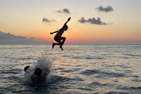 Child girl in swinsuit jumping. Summer vacation, travel and holiday concept. Family having fun on sea beachの写真素材