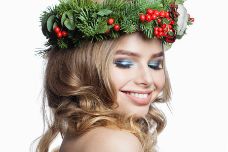 Cheerful healthy young woman with party makeup, long blonde curly hairdo and Christmas decor isolated on white background. Christmas beautyの写真素材