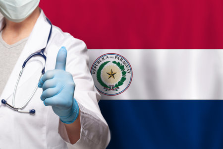 Paraguayan doctor's hand showing thumb up positive gesture on flag of Paraguay backgroundの写真素材