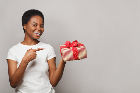 Beautiful happy young woman with gift present box standing on white backgroundの写真素材