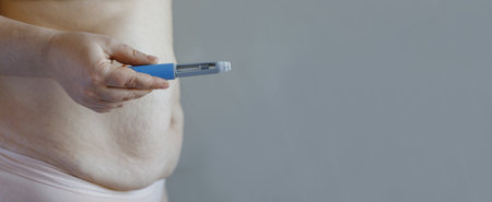 Human belly and hand closeup with Semaglutide Injection pen or insulin cartridge pen. Medical...