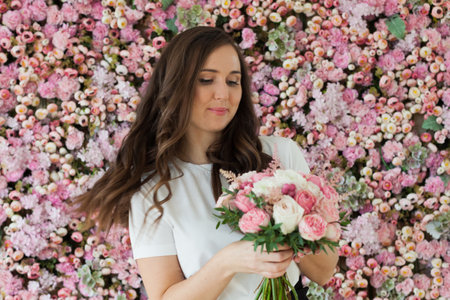 Gorgeous lady with flowers. Happy brunette woman indoor portraitの写真素材