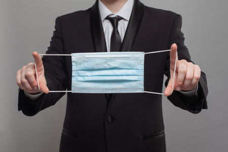 Business person holding medical protective mask to health protection and prevention from allergy, flu virus, epidemic and infectious diseasesの写真素材