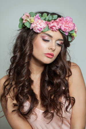Elegant brunette woman with fresh flower on her head. Spring, cosmetic, beauty, skin care and hair care conceptの写真素材