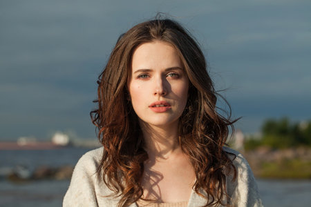 Healthy young woman model with brown hair and natural make-up walking along the shore of the resort on a spring morning. Happiness, balance, tranquility, emotion and mood conceptの写真素材