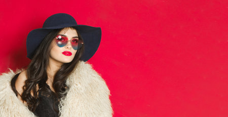 Attractive young adult woman fashion model with bright make-up and long wavy hair wearing blue hat...