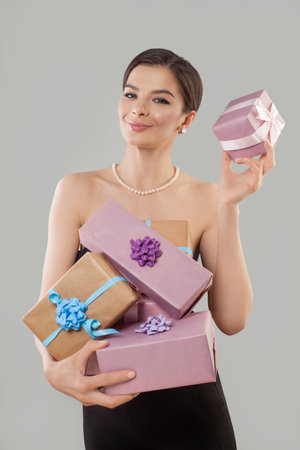 Happy excited young woman holding present gift box posing against white studio wall background.の写真素材