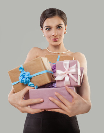Beautiful glamorous woman standing on a white background with a gift in her handsの写真素材