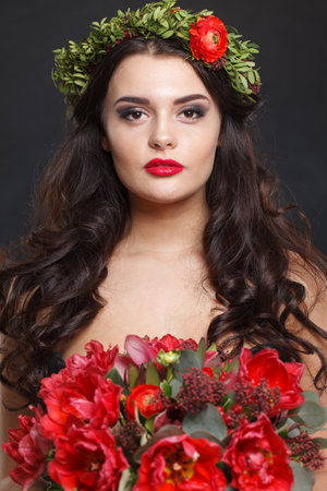 Beautiful woman with a wreath on her head from real flowers on black backgroundの写真素材