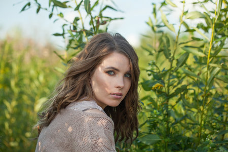Nice healthy young model woman with clean fresh skin, natural make-up and curly hairstyle against green grass background, outdoor portraitの写真素材