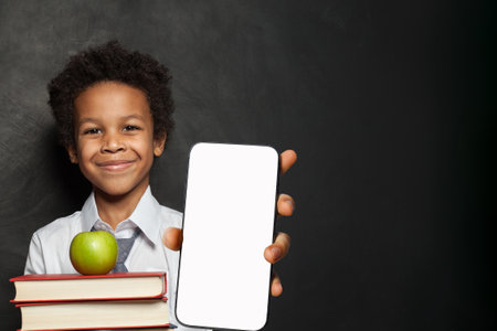 Back to school concept. Handsome child boy with mobile phone. Kid holding cell phone empty screen display. Smartphone display mockupの写真素材