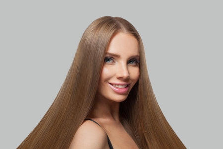 Fashion portrait of female model brunette with long hair and natural make-up posing isolated on white backgroundの写真素材