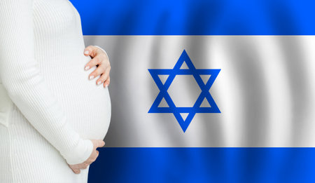 Pregnant woman belly against Israeli flag background. Demographics and pregnancy in Israel conceptの写真素材