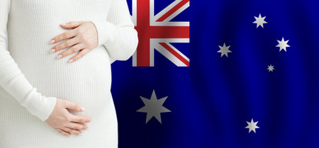 Demographics and pregnancy in Australia concept. Pregnant woman belly against Australian flag background.の写真素材