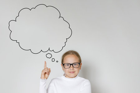 Child girl in school uniform pointing and looking up on gray banner backgroundの写真素材