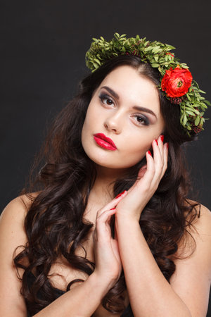 Cheerful healthy female model with shiny hair, make-up and spring flower on black backgroundの写真素材