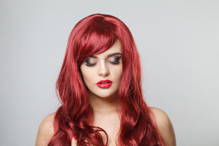 Pretty redhead female model with red shiny hair and make-up on white backgroundの写真素材