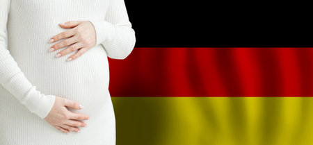 Pregnant woman belly against German flag background. Demographics and pregnancy in Germany conceptの写真素材