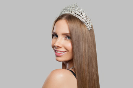 Nice glamorous jewelery woman wearing jewelry crown tiara with diamond posing against white studio wall backgroundの写真素材
