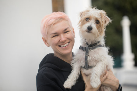 Smiling affectionate mature woman embracing pet dog in natureの写真素材