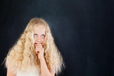 Thinking child girl looking up on black backgroundの写真素材