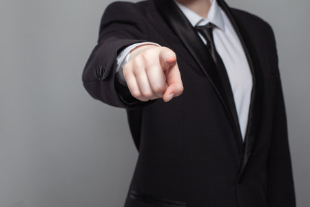 Businessman in black suit poing straightforward on camera.の写真素材